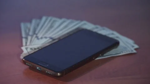 Incoming call to mobile phone on stack of green dollars Stock Footage 92534099
