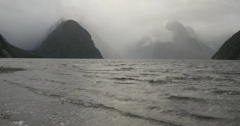 The incoming tide creates waves on a moody day in Milford Sound New Zealand Video stock 120371898