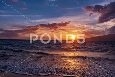 Incoming tide on Maui with firey sunset and distant Lanai Stock Photos