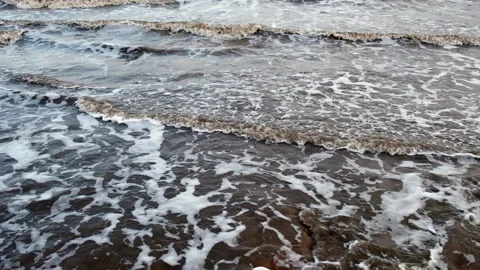 Incoming tide with moody slow motion waves looking out to sea with setting sun Stock Footage