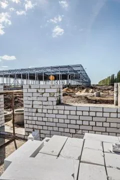 Incomplete brick wall with construction frame in background of construction site Stock Photos