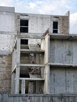 An incomplete structure behind a fence, featuring exposed concrete walls an.. Stock Photos