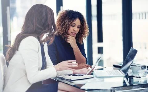 Incorporating technology into their team task. two businesswomen using a digital Foto stock
