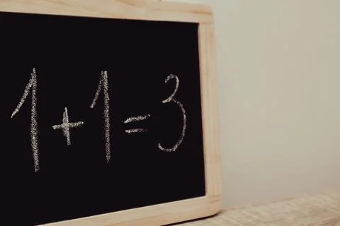 Incorrect math equation one plus one equals three written in chalk on a bla.. Stock Photos