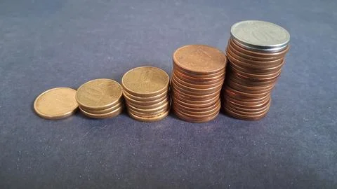 Increasing stacks of copper coins arranged on a dark grey background 스톡 사진