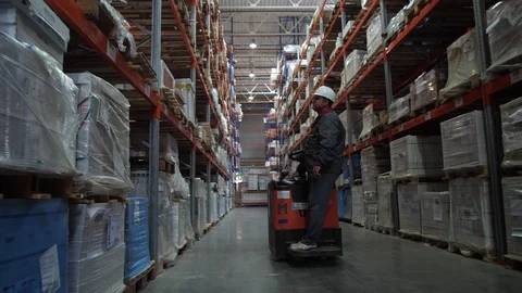Incredibly large logistic warehouse. A man on a car passes by the camera. 4K Stock-Footage 111766580