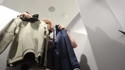 Indecisive shopper compares two outfits and struggles to choose the right one 動画素材 344856255