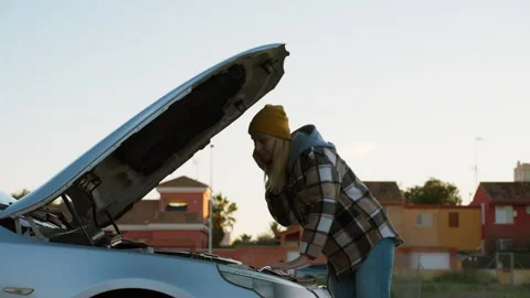 Independent woman checking stranded next to her car with popped hood, inspe.. Stock Footage 326095819