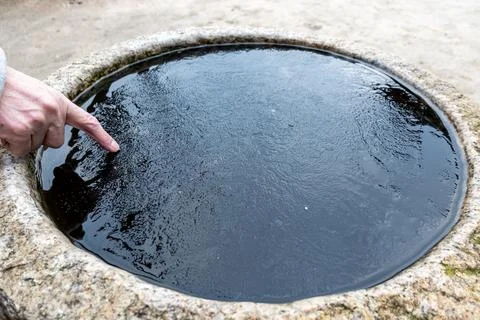 Index finger touching a thin sheet of ice formed on a cold day Foto stock