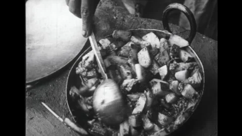 India 1940s: Woman cooks flat bread. Woman stirs pan full of food. Woman cuts Stock Footage 325631953