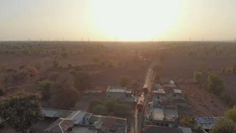 India, An Aerial shot of buses passing through Indian village during sunset Stock Footage