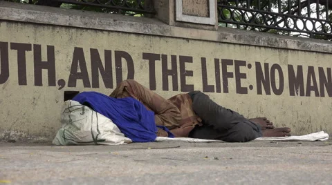India, Chennai, homeless man sleeps in front of Bible text, symbolic Stock Footage 48772353