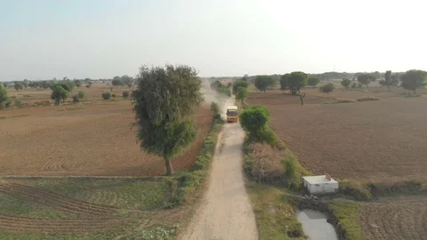 India, A drone camera view of a bus moving in a mud road Stock Footage 109241684