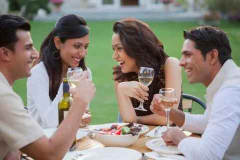India, Friends drinking wine at table on backyard Stock Photos