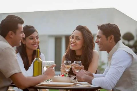 India, Friends drinking wine at table on backyard Stock Photos