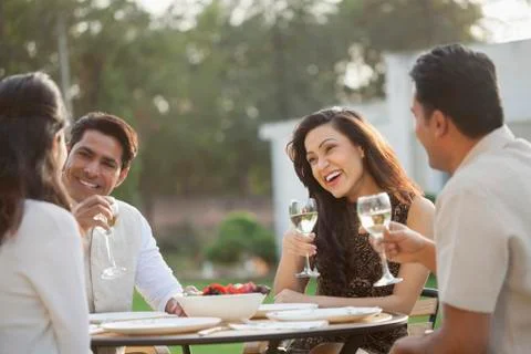 India, Friends drinking wine at table on backyard Stock Photos