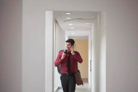 India, Man walking down corridor and talking on phone Stock Photos