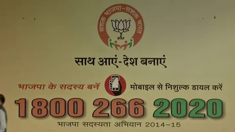 India, Narendra Modi BJP party headquarters man passes in front of billboard Stock Footage 77084918