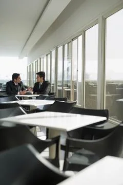 India, Two colleagues in discussion at table in cafeteria Stock Photos
