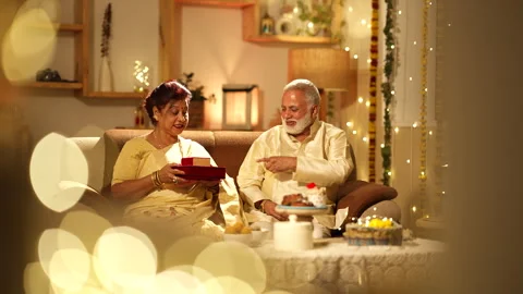 Indian aged couple talking and gave gift,sitting on sofa during diwali. Stock-Footage 252591620