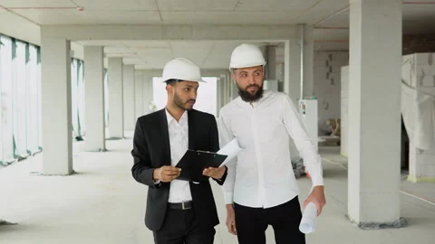 Indian and arabian builders engineers workers in helmets walking on construction Stock Footage 236476880