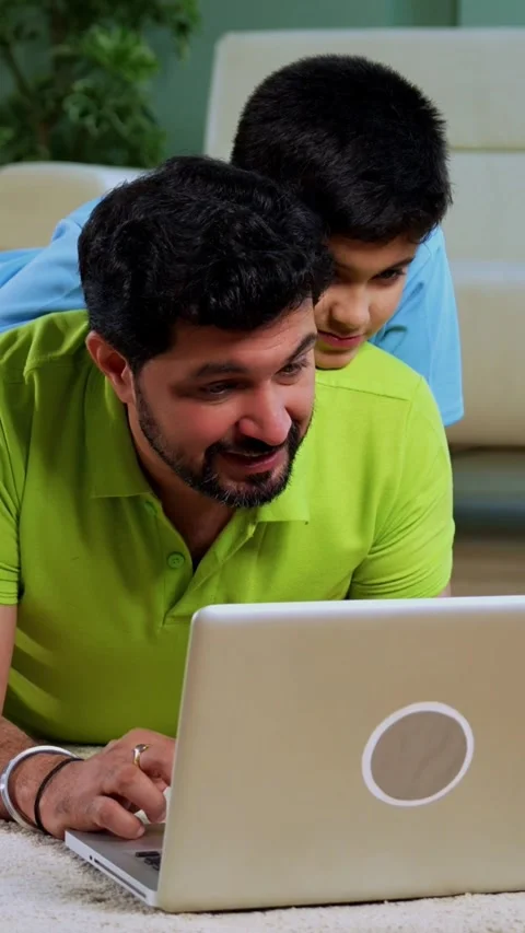 Indian asian man with son using laptop while lying on living room floor at home Stock Footage 342758118