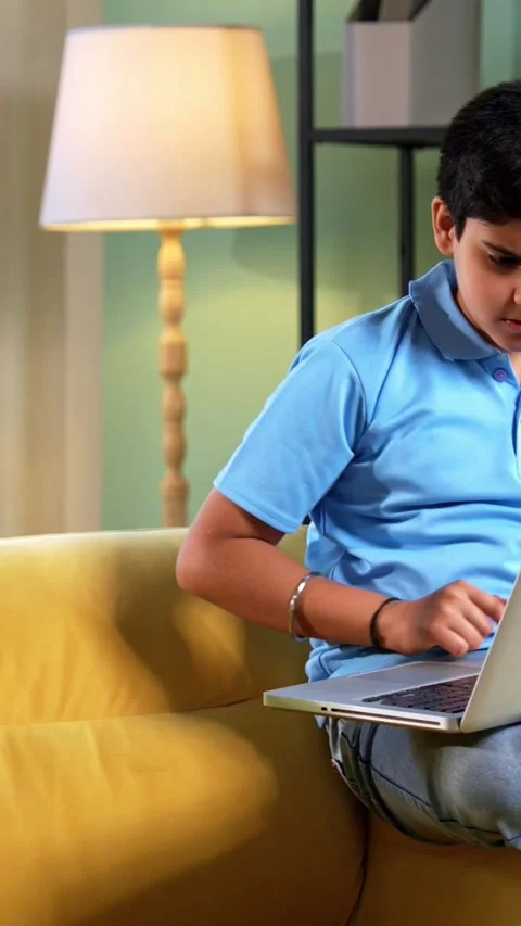 Indian asian son reading book as father works on laptop and guides him Stock Footage 342758031