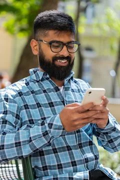 Indian bearded man using smartphone typing text messages in social media Stock Photos