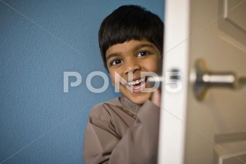 Indian boy laughing behind door Stock Photos
