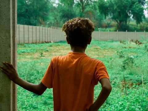 An indian boy looking wall structure at green grass field on natural backgrou Stock Photos