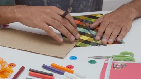 An Indian boy marking with a scale on a square patten craft paper Stock Footage 114863578