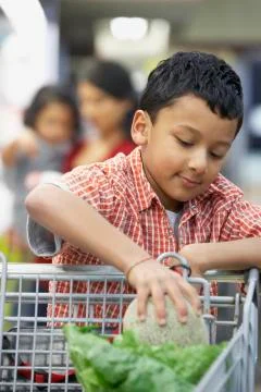 Indian boy putting fruit in shopping cart Stock Photos