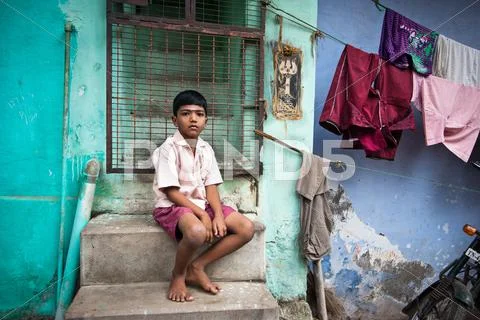 Indian boy sitting near colorful wall of his house at street Stock-Fotos
