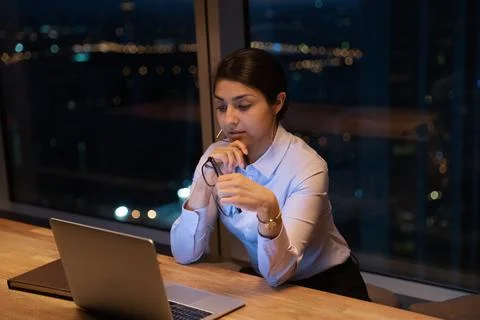 Indian businesslady looks at laptop reading e-mail thinks over information Stock Photos