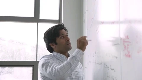 Indian businessman talking and writing on whiteboard in meeting Stock Footage