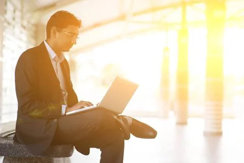 Indian businessman using laptop computer at railway station. Asian Indian ... Stock-Fotos