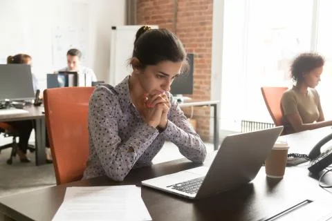 Indian businesswoman thinking of online problem solution looking at laptop Foto stock