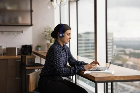 Indian businesswoman wear headphones use laptop communicating by videocall Stock Photos