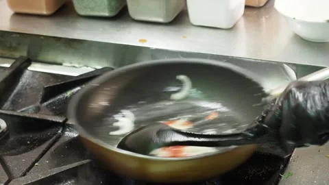 Indian chef sauteing onion and mixed vegetables with spices in pan over gas Video stock 346361703
