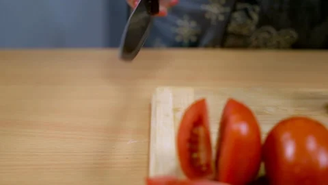 Indian chef using a sharp knife to slice a red and ripe tomato Stock Footage 158415033