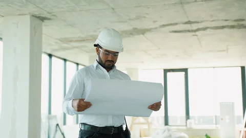 Indian civil engineer analyzing construction blueprints at building site Stock Footage 285671908