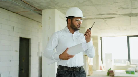 Indian civil engineer stands at a construction site holding blueprints and Stock Footage 285672354