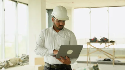 Indian construction engineer working on-site with laptop and helmet Stock Footage 285668353