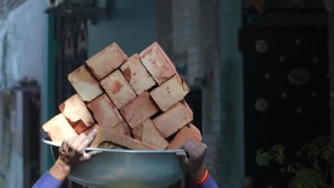 Indian Construction Laborer Carrying Heavy Load on Head at Worksite Stock Footage 327551653