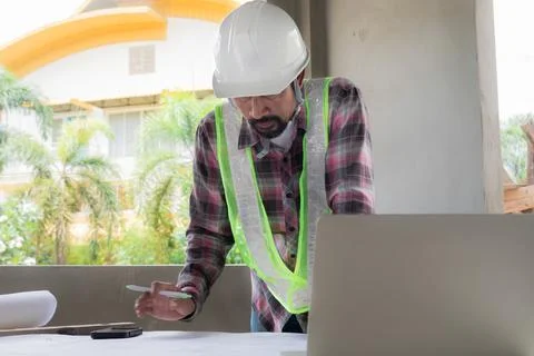 Indian construction project foreman reading blueprint paperwork on table in.. Stock Photos