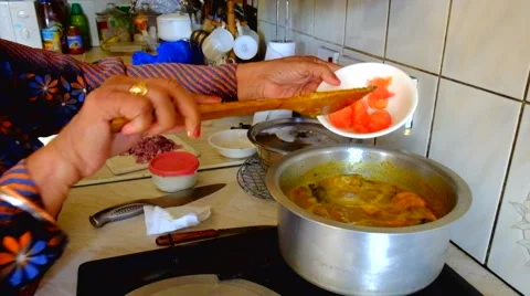 Indian cook adding indgredients to cooking pot &amp; stirring with wooden spoon Stock Footage 41532421
