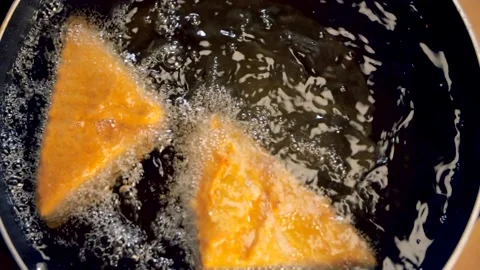 Indian cook's hand dropping a delicious bread Pakora in boiling hot oil Stock Footage 155043676