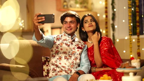 Indian couple clicking selfies while sitting on sofa during Diwali. Vídeo Stock 252593453