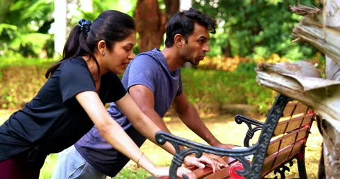 Indian couple doing pushups together on park bench maintaining fitness Stock Footage 342844784