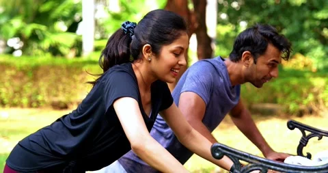Indian couple doing pushups together on park bench maintaining fitness Stock Footage 342844799